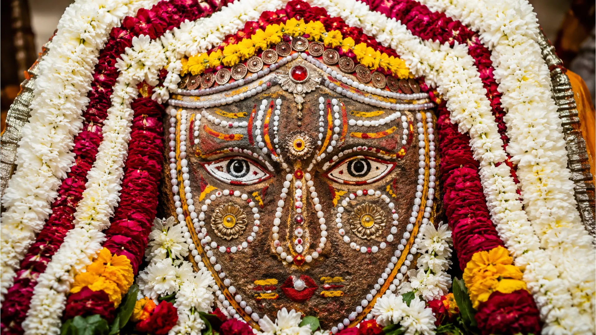 Sacred stone decorated with flowers, beads, and artistic facial design