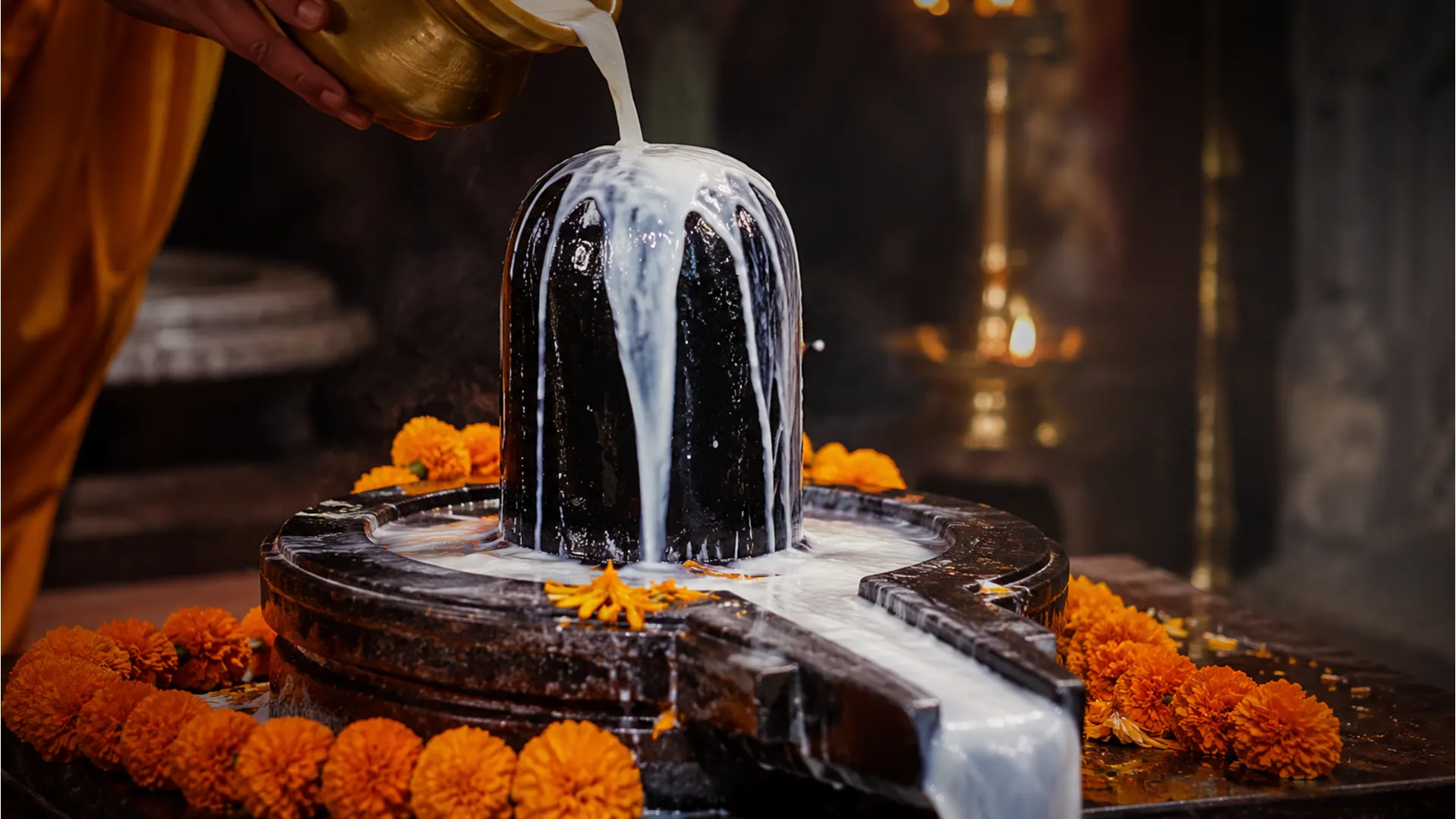Thick white milk being poured over a dark stone Shiva Lingam in a temple