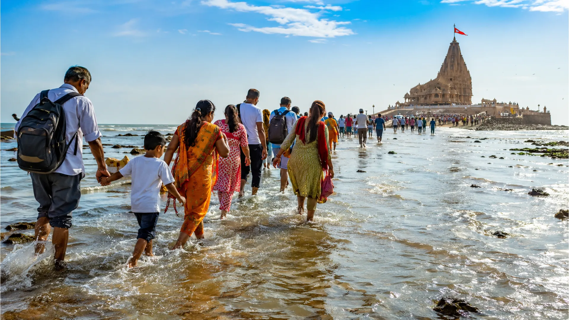 People walking through ankle-deep seawater toward Nishkalank Mahadev Temple during the start of low tide.