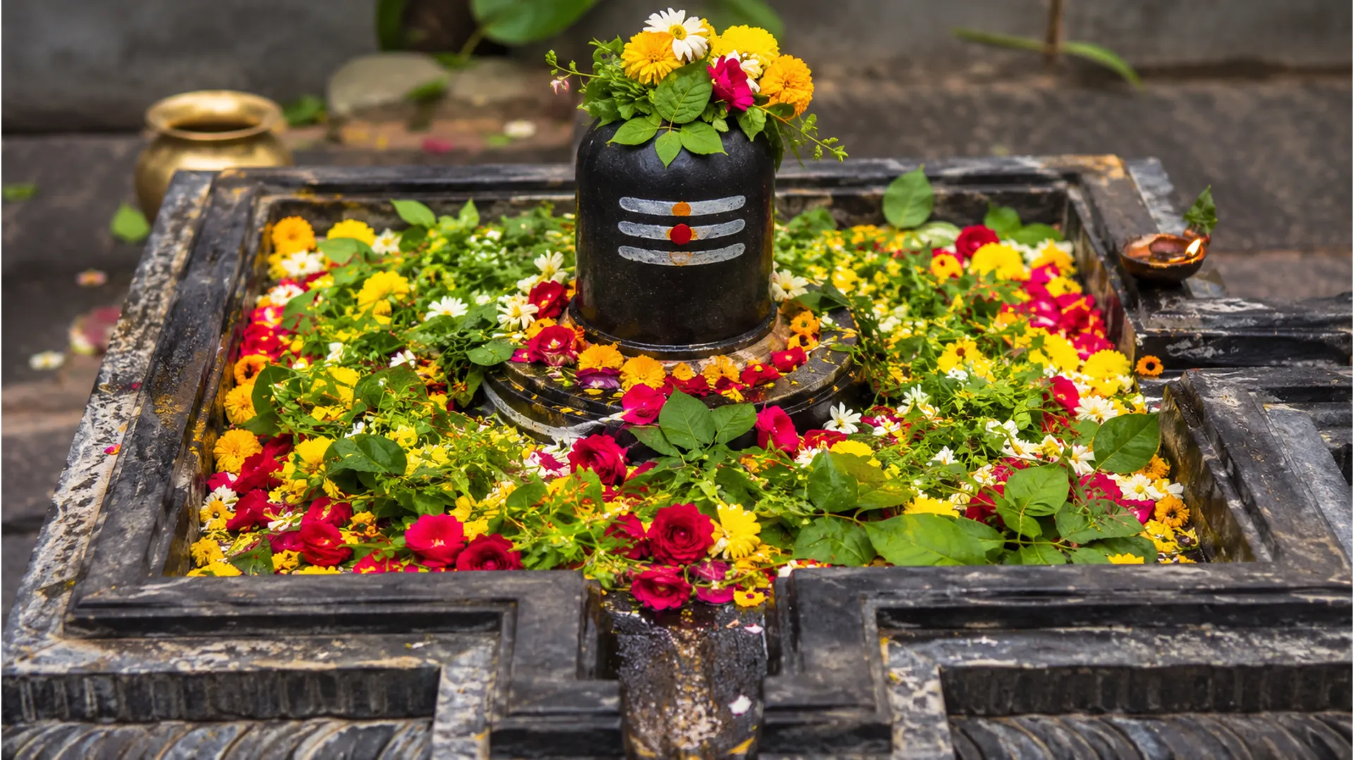 Shiva lingam placed in a square stone base filled with colorful flowers