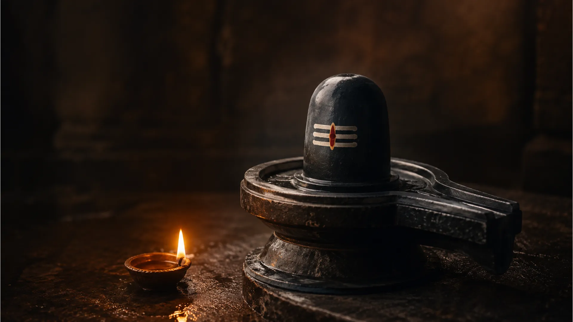 A serene minimalist setup of a small black shivling with a single oil lamp flame.