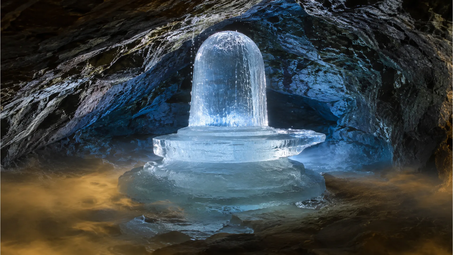 A natural ice Shivling formed inside a dark crystal cave with ethereal blue light filtering through.