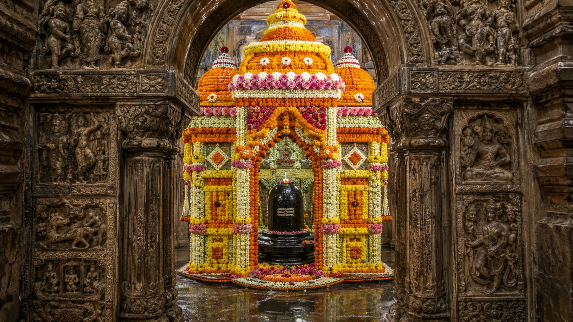 A vibrant Tarakeswar shivling image decorated with a massive festive canopy of colorful marigold and rose flowers.