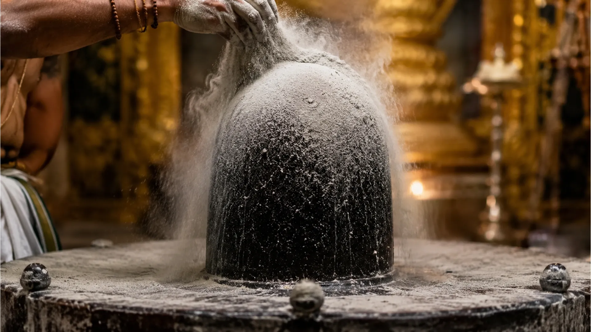 Sacred holy ash or Bhasma being offered over the dark stone Somnath Jyotirlinga