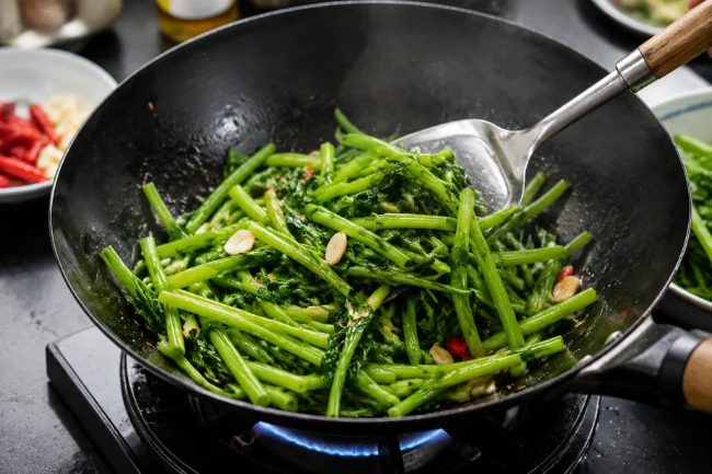 Yalla Choy cooking in wok with garlic and chili